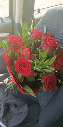 a bouquet of red roses sits in a car