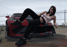 a woman laying on the front of a red car