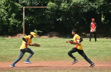 two boys are playing a game of cricket and one of them is wearing a yellow shirt