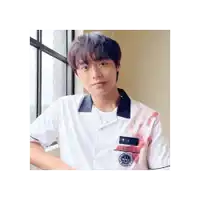 a young man wearing a white shirt with blood on it is standing next to a window .