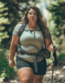 a woman wearing a backpack and shorts is walking down a trail