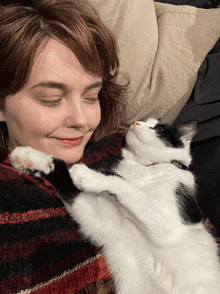 a woman holds a black and white cat with a collar that says ' old ' on it