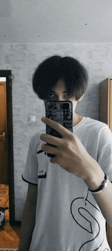 a young man taking a picture of himself in front of a mirror with his phone