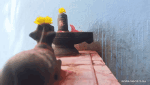 a statue of a cow and a shiva lingam with a yellow flower on top