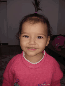 a little girl wearing a pink sweater smiles for the camera on february 1 2020