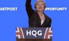 a woman stands behind a podium that says hqq