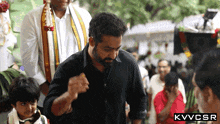 a man in a black shirt stands in front of a crowd with the letters kvvcsr on the bottom right