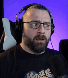 a man with a beard wearing headphones and a black shirt with chinese characters on it