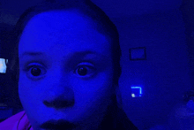 a girl with a surprised look on her face is standing in front of a blue light