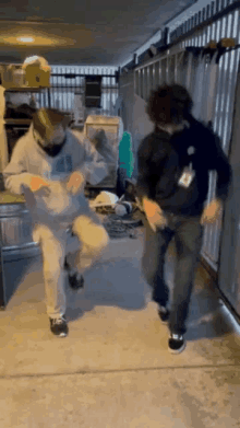 two men are dancing in a hallway with a fence in the background