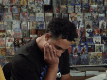 a man sitting in front of a wall of comic books including one that says ' mighty hulk ' on it