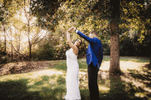 a bride and groom are dancing in front of trees