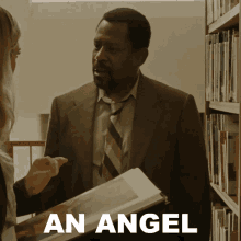 a man in a suit and tie is talking to a woman in front of a bookshelf that says an angel on it