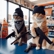 two cats wearing beanies and bandanas are holding guns in front of a gas station sign that says gutsig