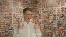 a man wearing glasses and a white shirt is standing in front of a wall covered in comic books .