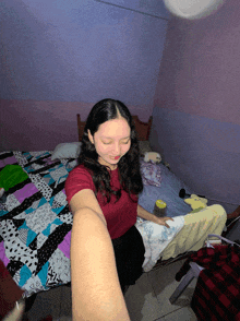 a girl taking a selfie in a bedroom with a purple wall