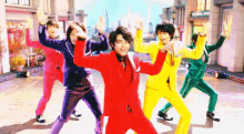 a group of men in colorful suits are dancing in front of a sign that says colorful eye