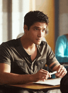 a young man with a tattoo on his arm sits at a desk