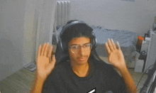 a young man wearing headphones and glasses is sitting in front of a computer .