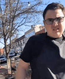 a man wearing glasses and a black shirt is standing in front of a sign that says cafe