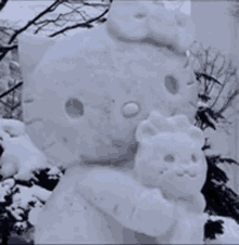 a hello kitty snow sculpture is holding a teddy bear .