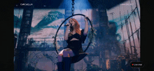 a woman singing into a microphone while sitting on a hoop with the words lana del rey on the bottom