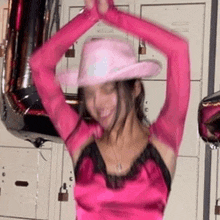 a woman in a pink cowboy hat and pink gloves is dancing .