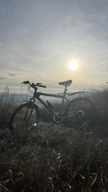 a bicycle is parked in a field with the sun shining through the clouds