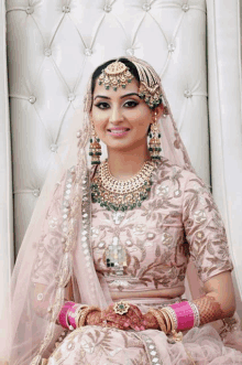 a bride in a pink and gold dress is sitting on a chair