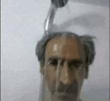 a man is taking a shower with water pouring from a shower head on his head .