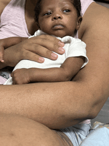 a woman is holding a baby in her arms and the baby has a serious look on his face