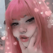 a girl with pink hair and freckles is making a funny face with her hand on her face .