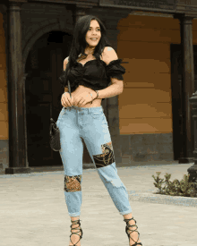 a woman wearing a black off the shoulder top and leopard print jeans