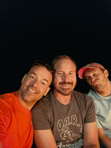 three men are posing for a picture and one is wearing a shirt that says oar