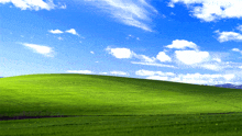 a lush green hillside with a blue sky and white clouds