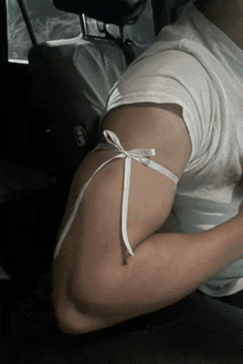 a man in a white shirt has a white ribbon around his arm