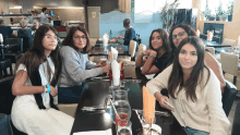 a group of girls are sitting at a table in a restaurant eating