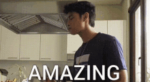 a young man is standing in a kitchen with the words amazing written on the bottom of the image .