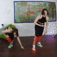 two women are dancing in front of a dinosaur painting