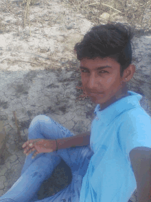 a boy in a blue shirt sits on the ground