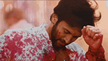 a man with blood on his shirt is covering his face with his hands