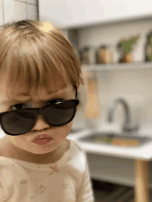 a little girl wearing sunglasses making a face