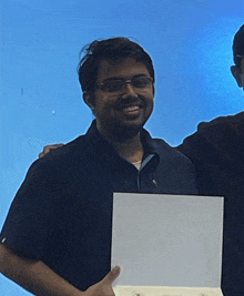 a man in a blue shirt is holding a white box and smiling