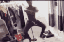 a blurry picture of a person dancing in a room with clothes hanging on the wall