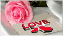 a pink rose sits next to a card with the word love on it