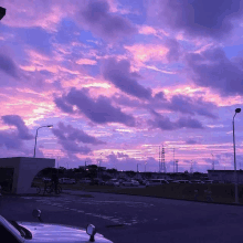 a person riding a bike in a parking lot with purple clouds in the sky