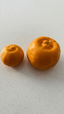 two oranges are sitting on a counter and one has a hole in it