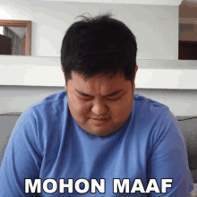 a man in a blue shirt with the words mohon maaf written on his chest