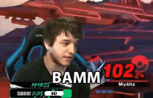 a man sitting in a chair with the words bamm 102 on the screen behind him