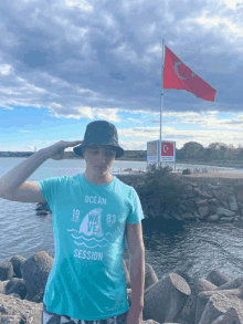 a man wearing a blue ocean wave session shirt salutes